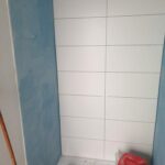 Pose de la faïence de la douche sur panneaux d'étanchéité pendant les travaux à Saint-Orens-de-Gameville