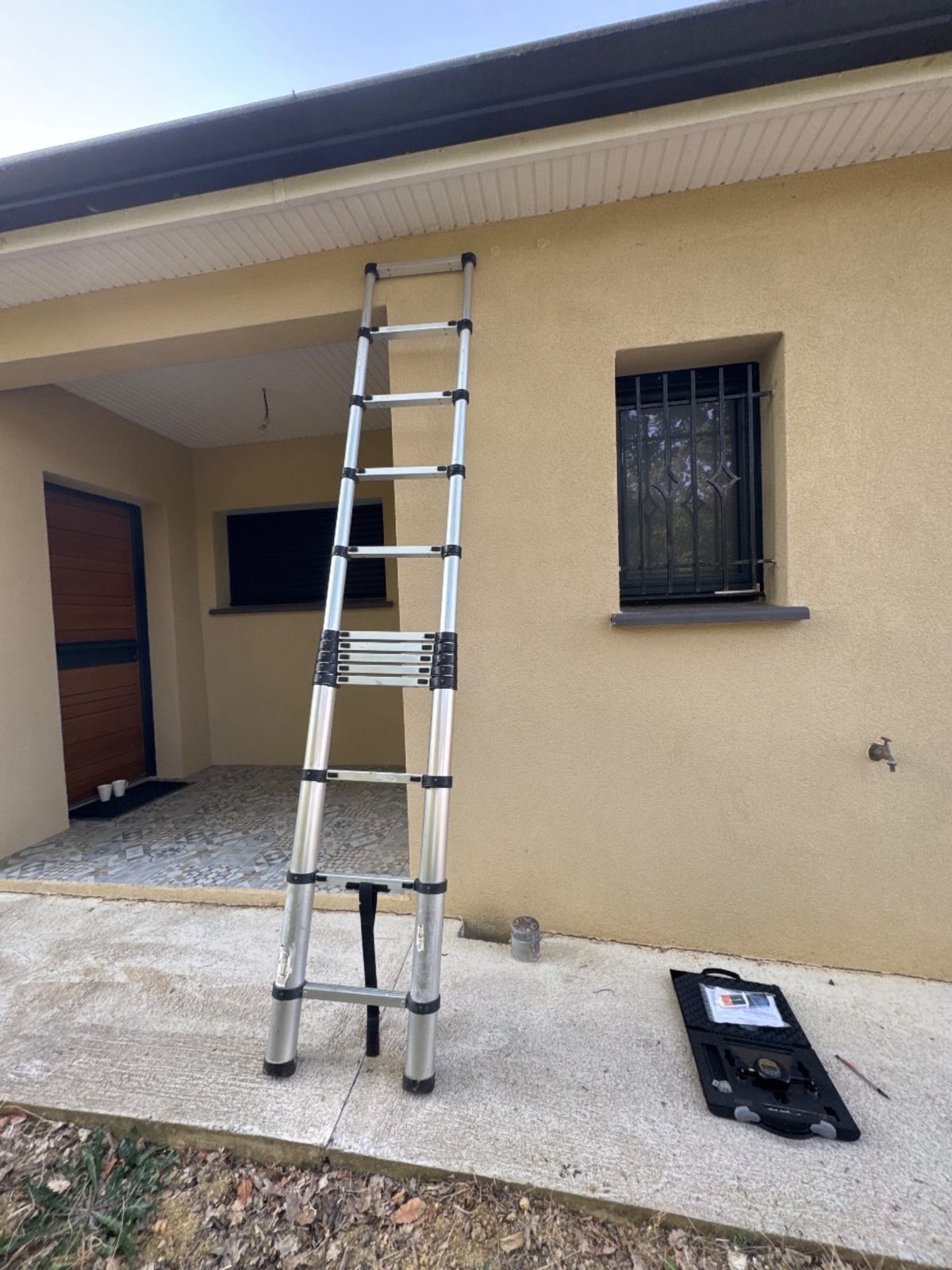 Mallette du fissuromètre et échelle au pied de la façade à instrumenter à Belflou