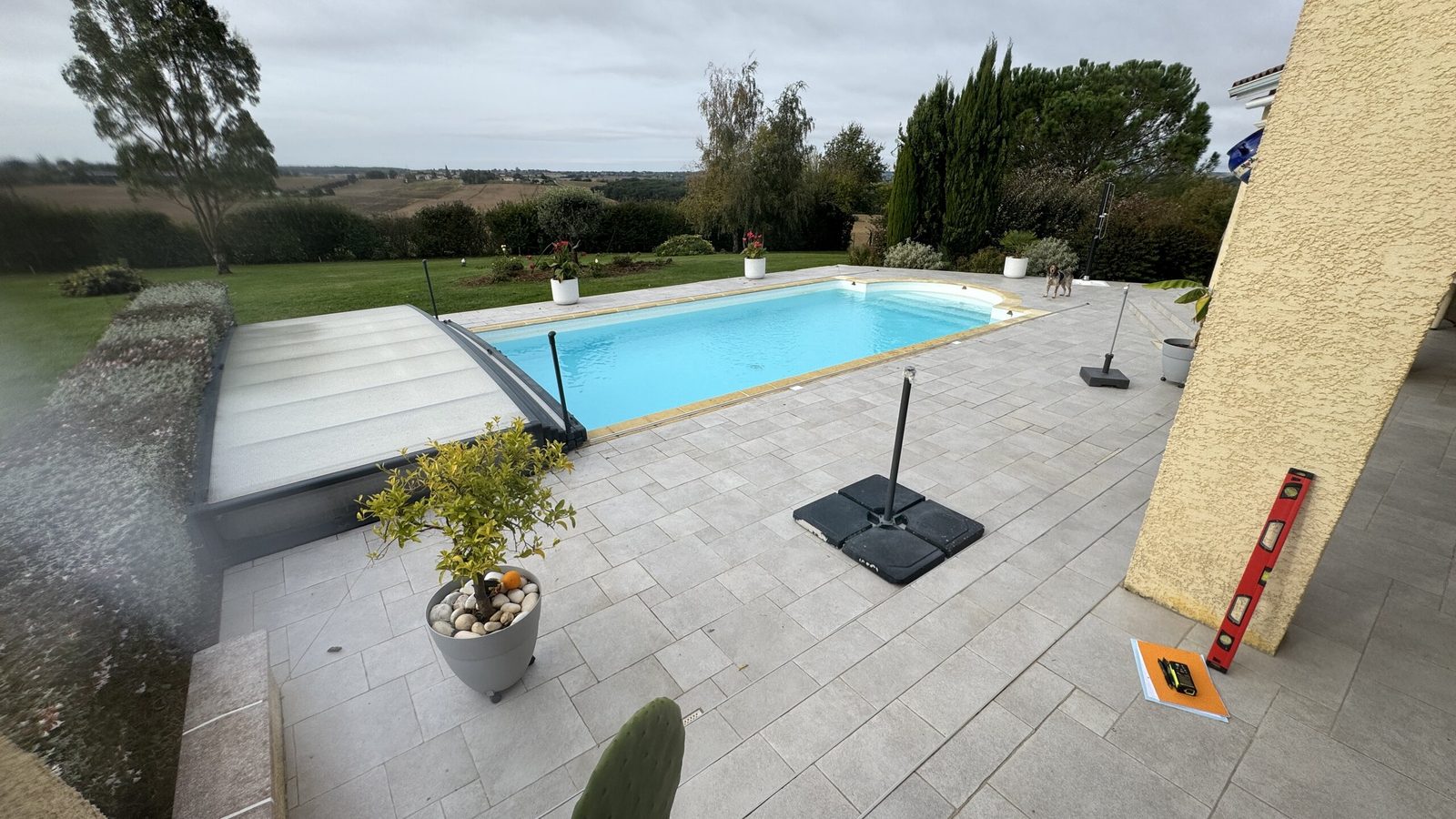 Vue d'ensemble de la piscine et de sa plage carrelée avant travaux à Encausse