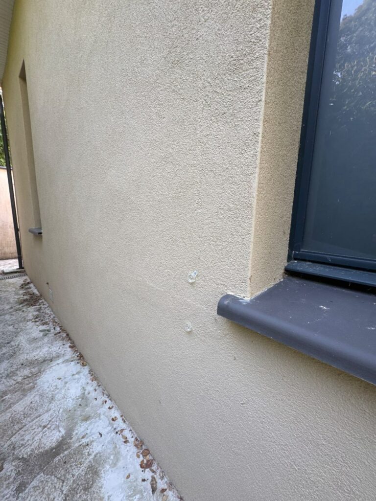 Platines de fixation posées de part et d'autre d'une fissure près d'un angle de fenêtre à Belflou
