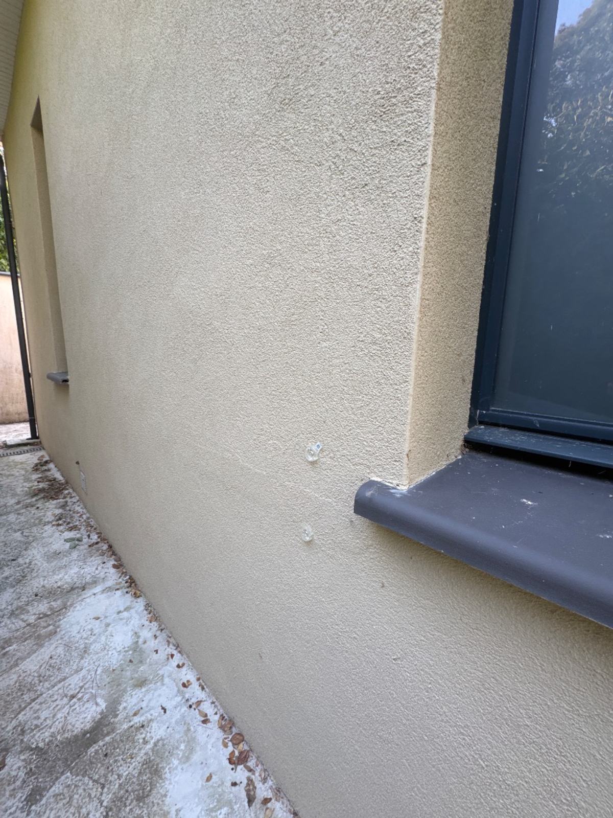 Platines de fixation posées de part et d'autre d'une fissure près d'un angle de fenêtre à Belflou