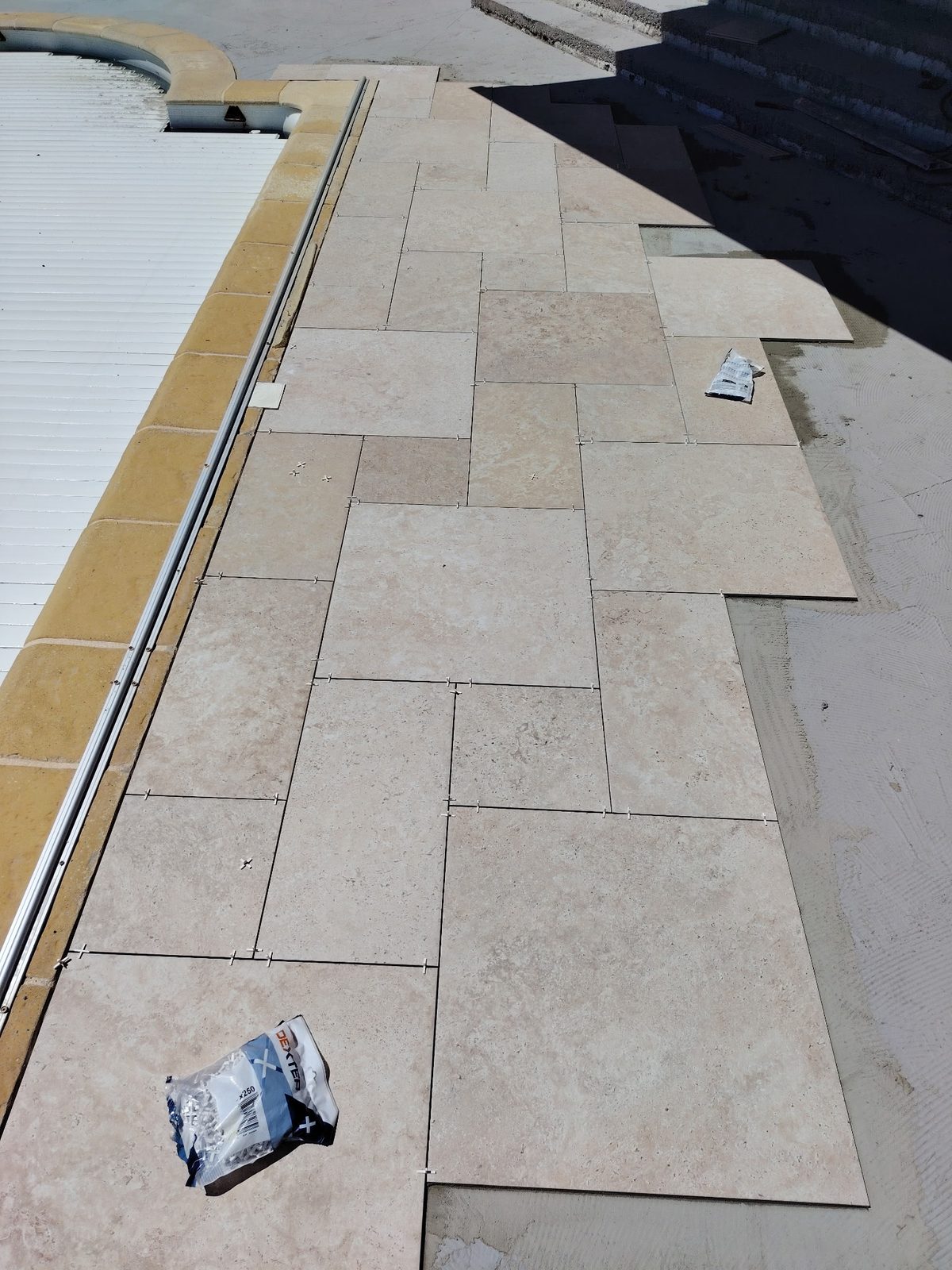 Pose du carrelage en opus sur la plage de piscine pendant les travaux à Encausse
