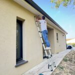 Technicien MPYBS fixant une platine de fissuromètre en haut de façade à Belflou